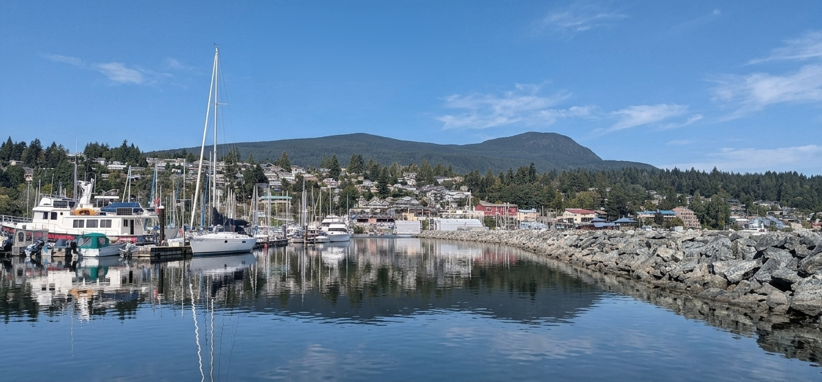 Gibsons harbour with sailboats, the town hillside, and the coastal mountains behind
